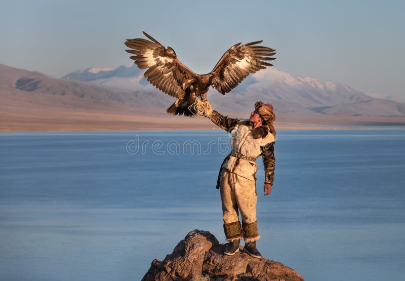 Young kazakh eagle hunter with his golden eagle