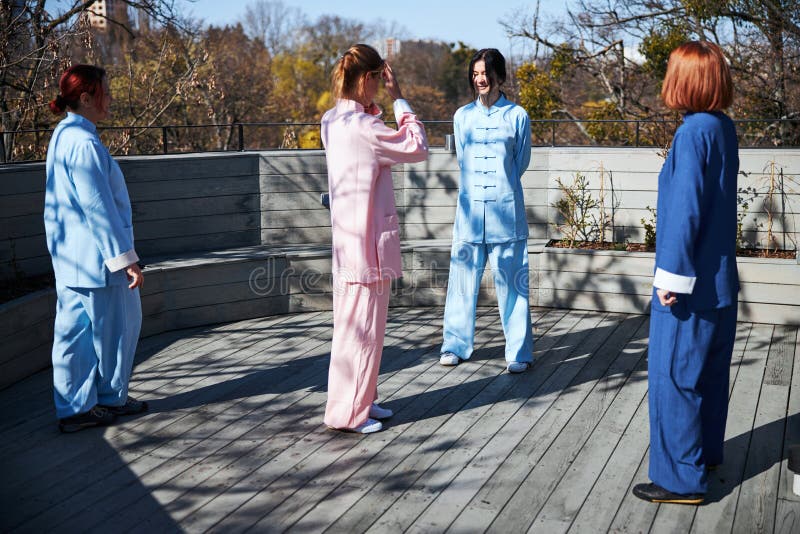 Young ladies wearing traditional Chinese clothes standing on a sunny terrace and talking. Qigong class stock images, royalty-free photos and pictures