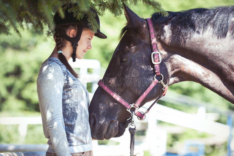 Young lady equestrian looking with love on her chestnut horse