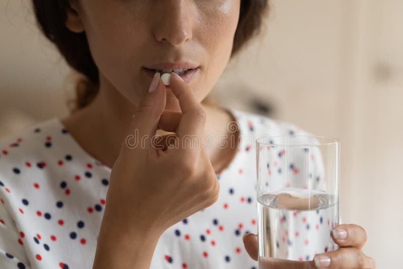 Young lady hold glass of water prepare to swallow pill