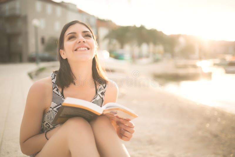 Young lady reading a book on a beach at sunset.summer holidays and vacation stock images Young lady reading a book on a beach at sunset.summer holidays and vacation stock images