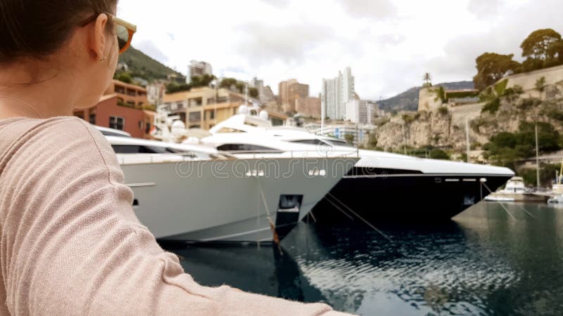 Young lady sitting on bench near sea, looking at yachts parked at pier, relax stock photos Young lady sitting on bench near sea, looking at yachts parked at pier, relax stock photos