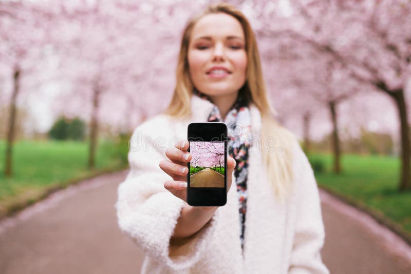 Young lady at spring park showing pictures on her mobile phone