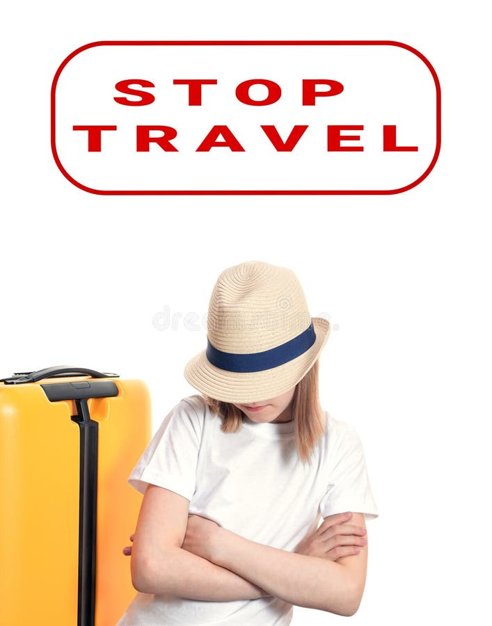 Young lady tourist with hat on face keeps hands crossed on chest near yellow suitcase on wheels isolated on white. Stop travel royalty free stock image Young lady tourist with hat on face keeps hands crossed on chest near yellow suitcase on wheels isolated on white. Stop travel royalty free stock image