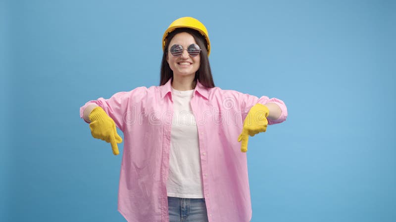 Young lady worker in yellow hard hat, american glasses and gloves