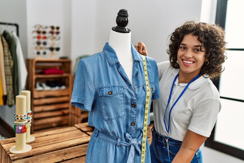 Young Latin Shopkeeper Woman Smiling Happy Measuing Clothes on Manikin ...