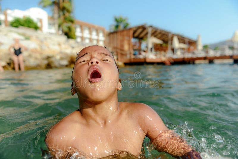 Young little girl floating at sea and showing hand calling for help when she playing on summer holiday and drowning in water. The girl drowned and the water hit her nose when she bathed. Young little girl floating at sea and showing hand calling for help when she playing on summer holiday and drowning in water. The girl drowned and the water hit her nose when she bathed