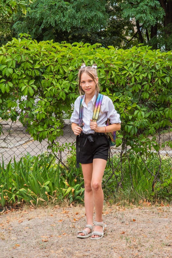 A young little girl preparing to walk to school. Teenager in autumn in the schoolyard