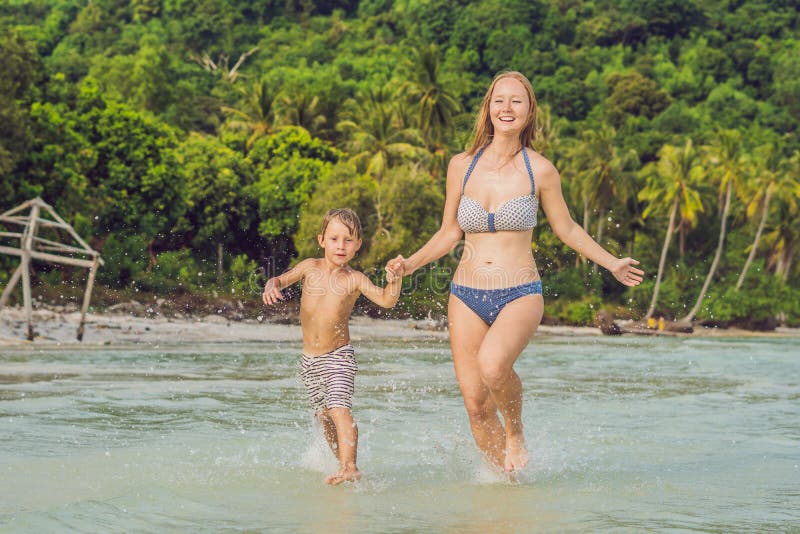 Young loving mother and her little son playing on the beach