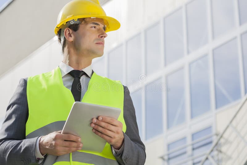 Young male architect with digital tablet looking away outside building stock images