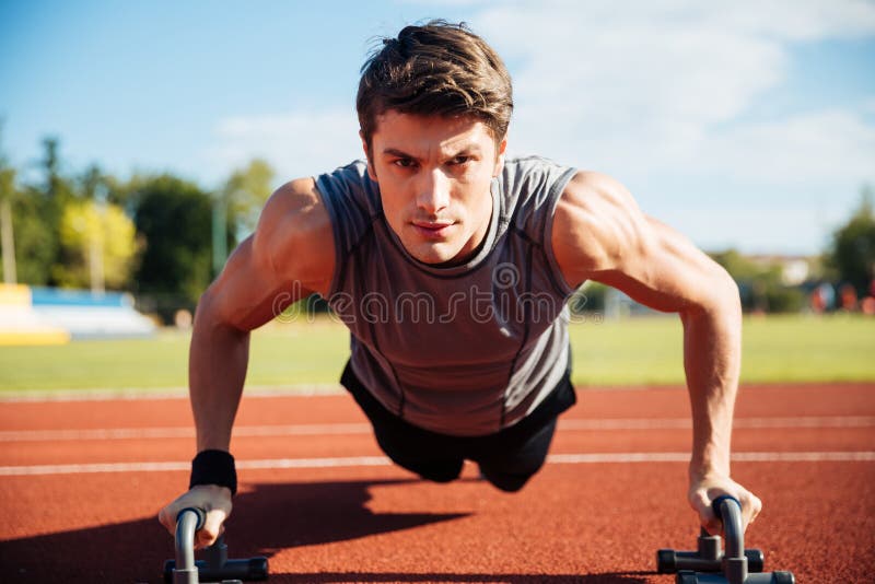 Young male athlete makes push ups on a racetrack stock image