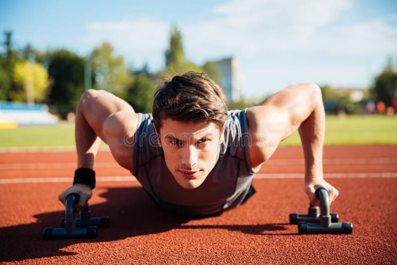 Young male athlete makes push ups on a racetrack royalty free stock photo