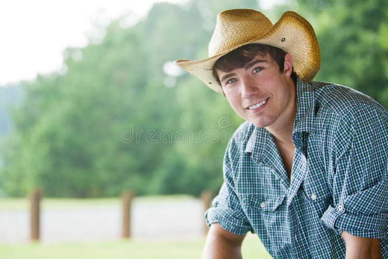 Un giovane uomo attraente vestito da cowboy che sorride alla telecamera esterna.