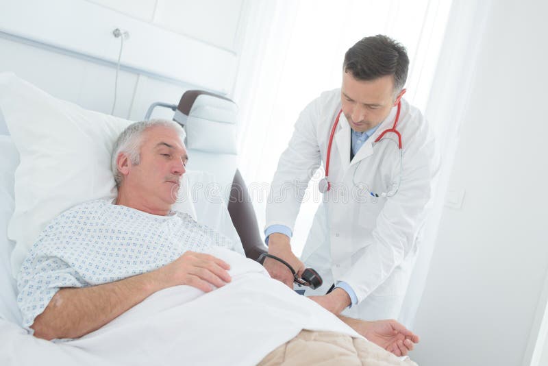 Young male doctor checking blood pressure senior male patient stock photo Young male doctor checking blood pressure senior male patient stock photo