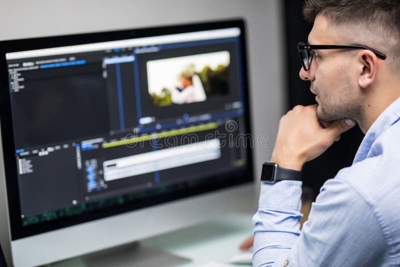 Young Male Editor Editing Video on Computer at Workplace Office Stock