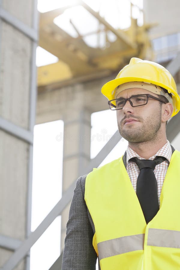 Young Male Engineer Wearing Hard Hat Looking Away at Construction Site