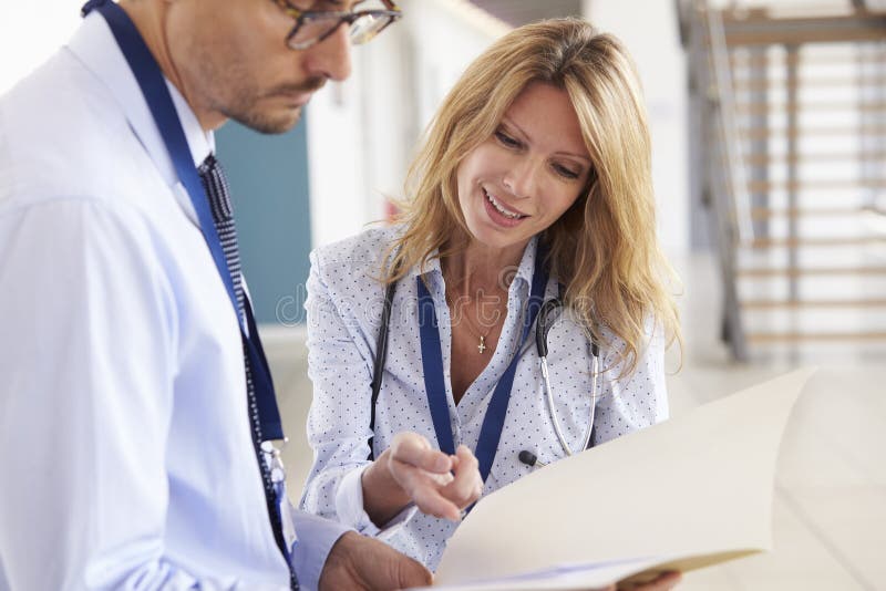 Young male and female doctors consulting notes at meeting