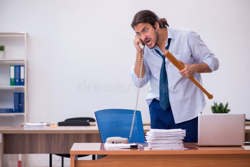 Young male furious employee holding baseball bat in the office royalty free stock photography
