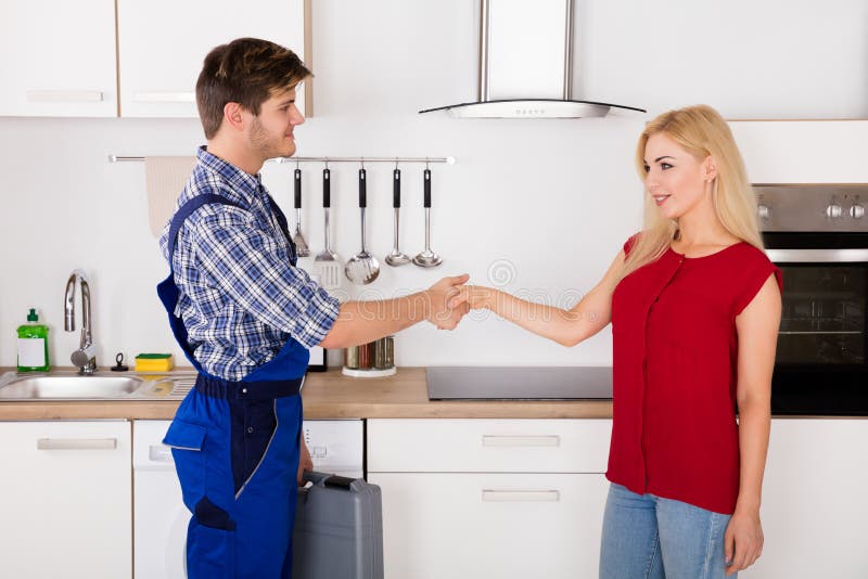Repairman Shaking Hands With Woman In Kitchen