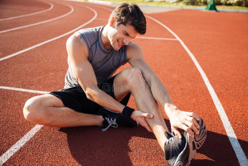Young male runner suffering from leg cramp on the track stock images