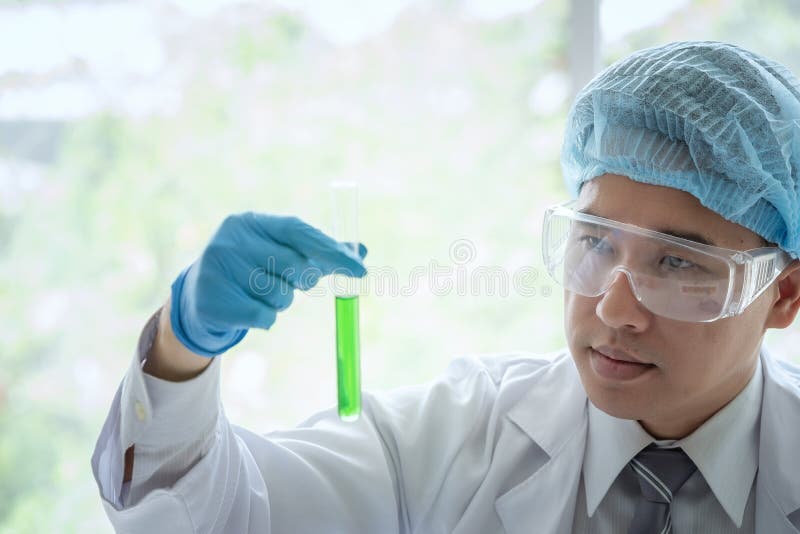 Young male scientist standing in lab worker making medical research in modern laboratory. Scientist holding test tube with stock photography Young male scientist standing in lab worker making medical research in modern laboratory. Scientist holding test tube with stock photography