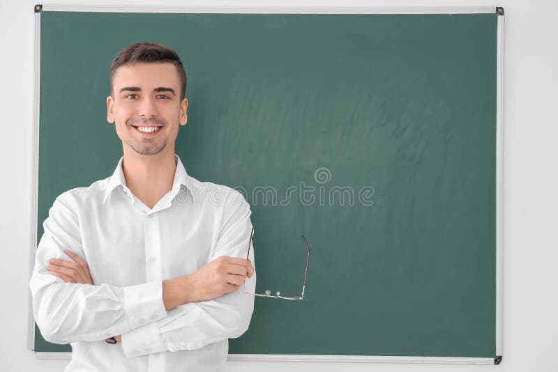 Young male teacher standing near blackboard stock image Young male teacher standing near blackboard stock image