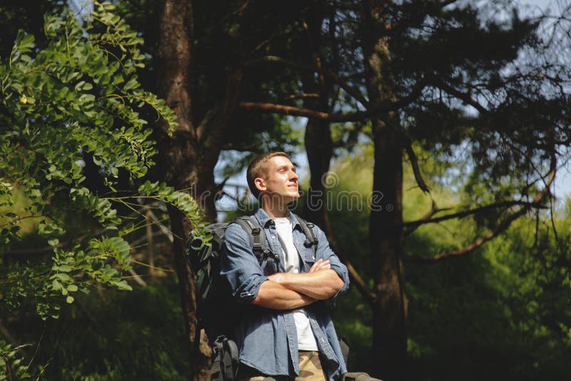 Young male traveler with backpack trekking in mountains and forests. Wild nature is the best place to find yourself stock photo