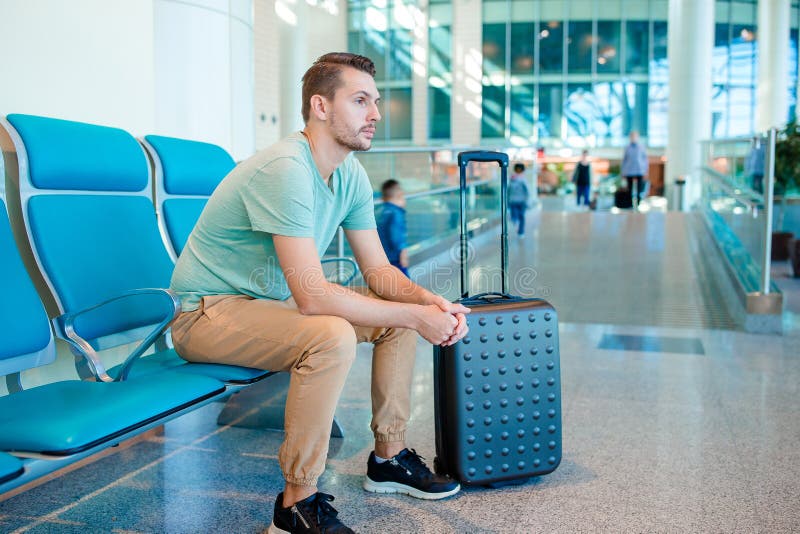 Young man in an airport lounge waiting for flight aircraft.