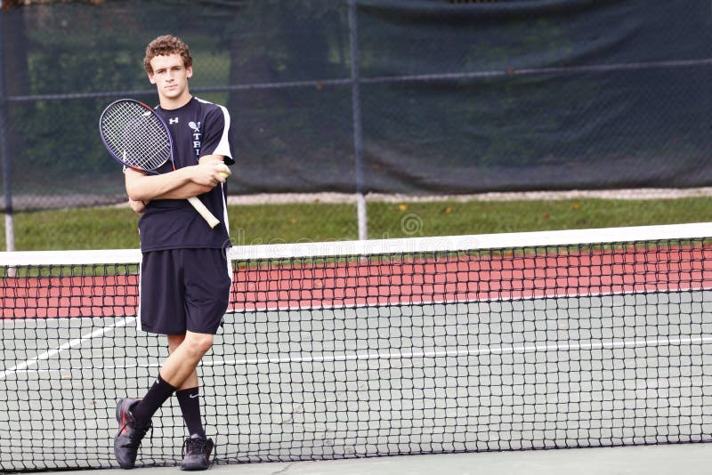 A young man in a blue and white shirt holding a tennis racket. A young man in a blue and white shirt holding a tennis racket.