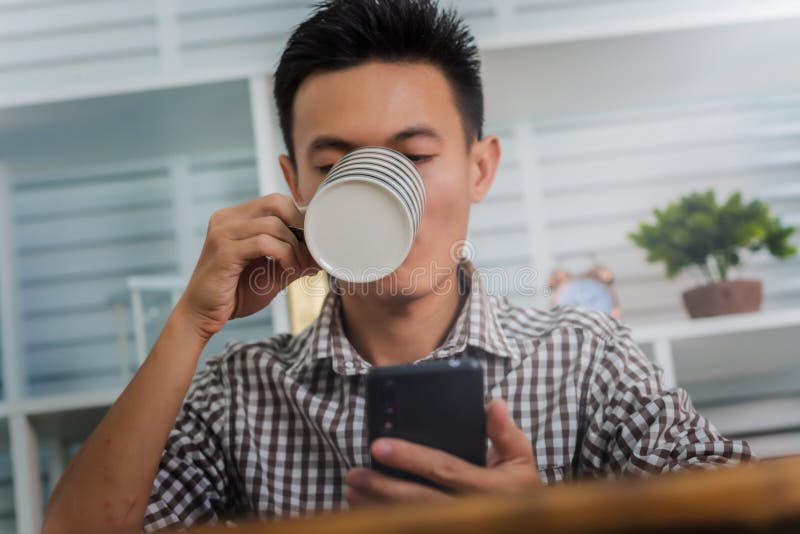 Young man asian using mobile phone working from home after coronavirus or covid-19 pandemic royalty free stock images Young man asian using mobile phone working from home after coronavirus or covid-19 pandemic royalty free stock images