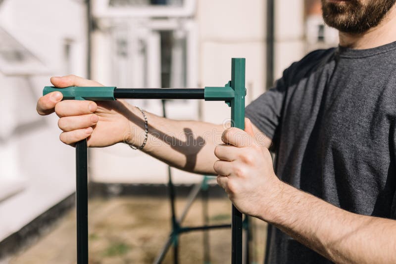 A young man assembling a greenhouse frame outdoors stock photography