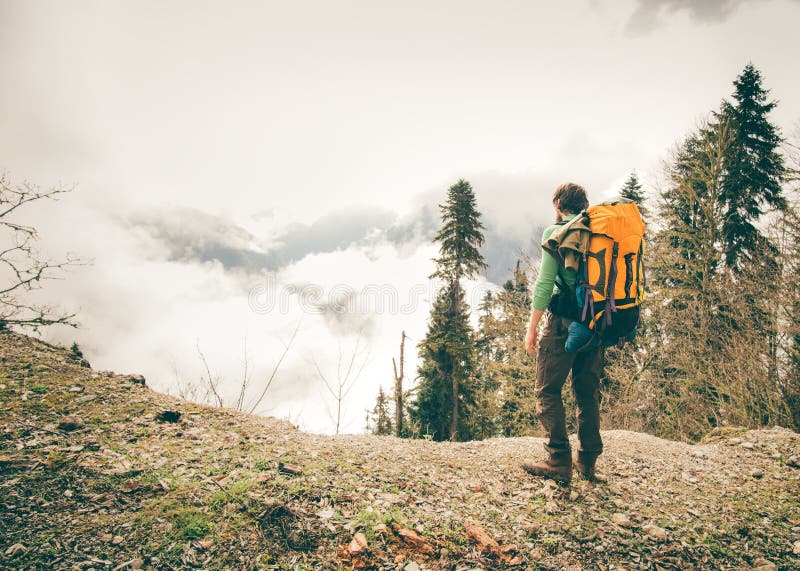 Young Man with backpack relaxing outdoor. With foggy mountains on background Lifestyle Travel concept Summer vacations stock image Young Man with backpack relaxing outdoor. With foggy mountains on background Lifestyle Travel concept Summer vacations stock image