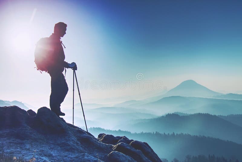 Young man with backpack standing on top of mountain and enjoying mountain view. Hiker on the mountain top. Sport and active life stock image Young man with backpack standing on top of mountain and enjoying mountain view. Hiker on the mountain top. Sport and active life stock image