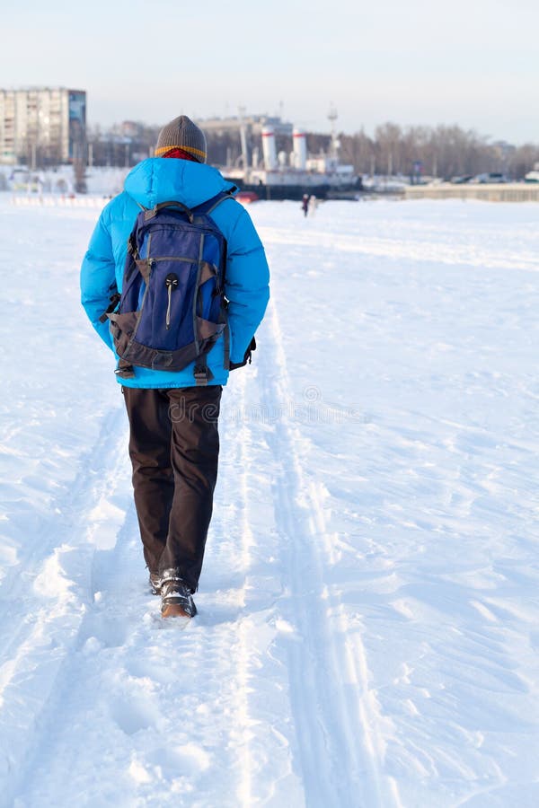 Young Man with Backpack Walking on Snow Cover. His Back To the Camera ...