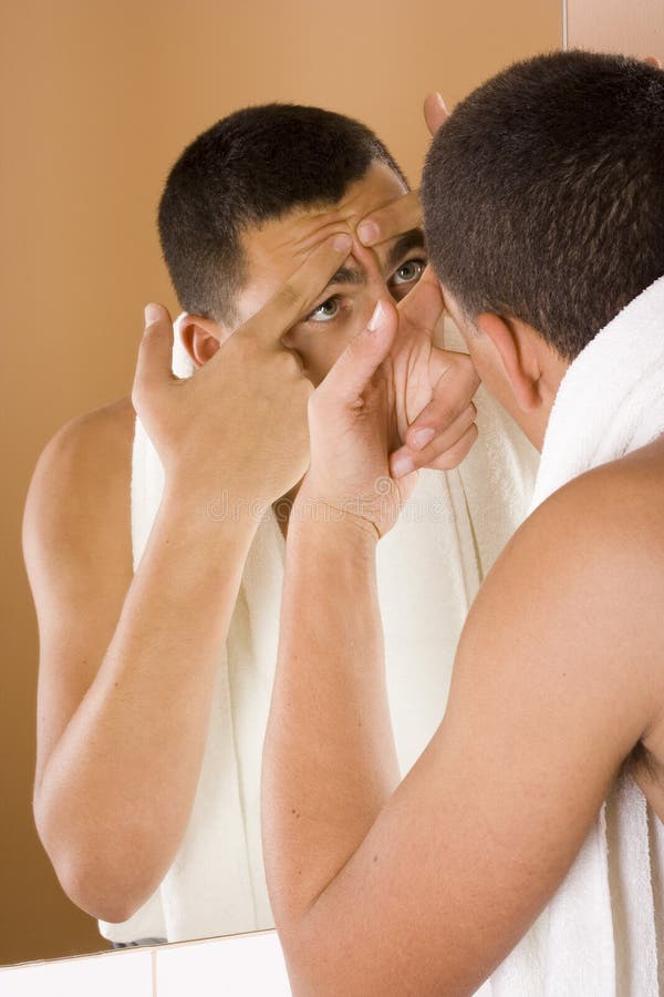 Young man in the bathroom s mirror cleaning his skin