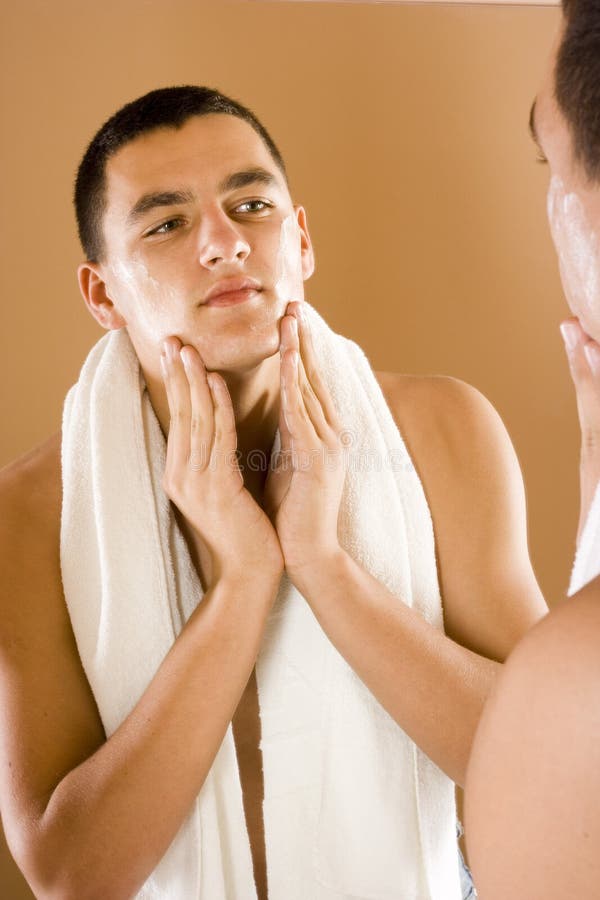 Young man in the bathroom s mirror using cream