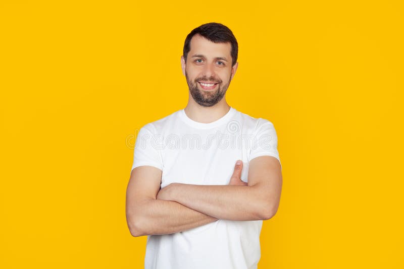 Young man with beard in white t-shirt happy face smiling with crossed arms looking at the camera. Positive man stands on isolated