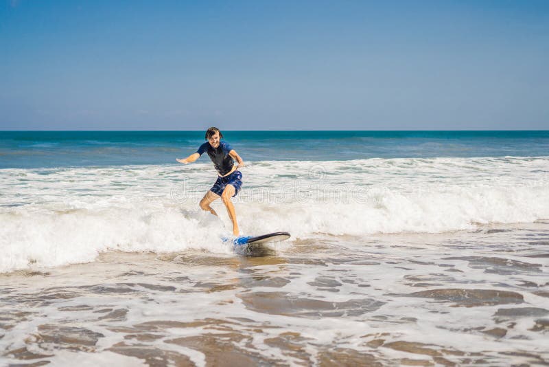 Young man, beginner Surfer learns to surf on a sea foam on the B stock photo Young man, beginner Surfer learns to surf on a sea foam on the B stock photo