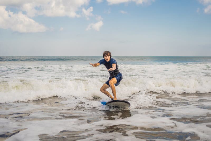 Young man, beginner Surfer learns to surf on a sea foam on the B stock image Young man, beginner Surfer learns to surf on a sea foam on the B stock image