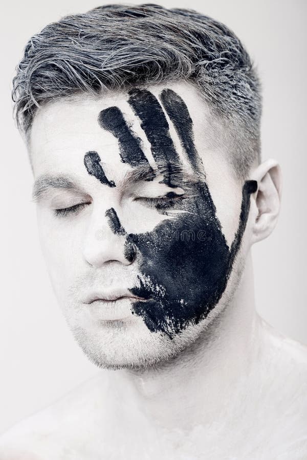 Young man with black hand print on white face. Closeup Portrait. Professional Fashion Makeup. fantasy art makeup royalty free stock photo Young man with black hand print on white face. Closeup Portrait. Professional Fashion Makeup. fantasy art makeup royalty free stock photo