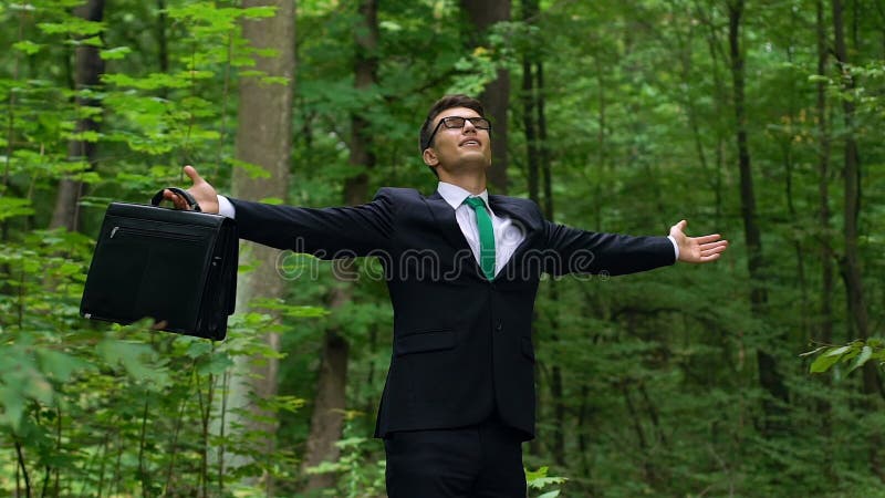 Young man in business suit breathing deep outdoors, abstracting from city stress