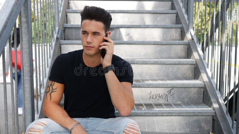 Young man calling on cellphone outdoors in urban setting stock photos Young man calling on cellphone outdoors in urban setting stock photos