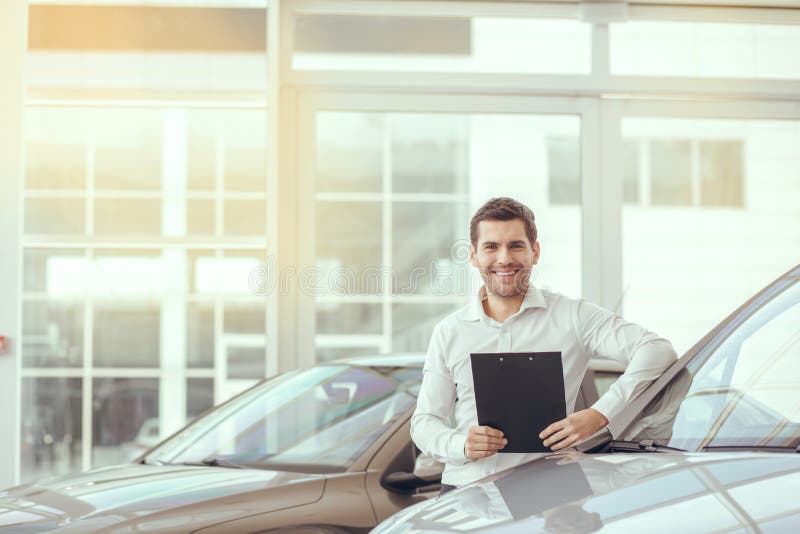 Young man in a car rental service holding contract. Young man in a car rental service holding contract