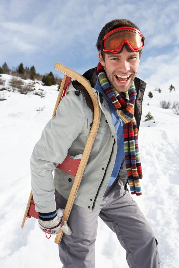 Young Man Carrying Sled In Alpine Landscape