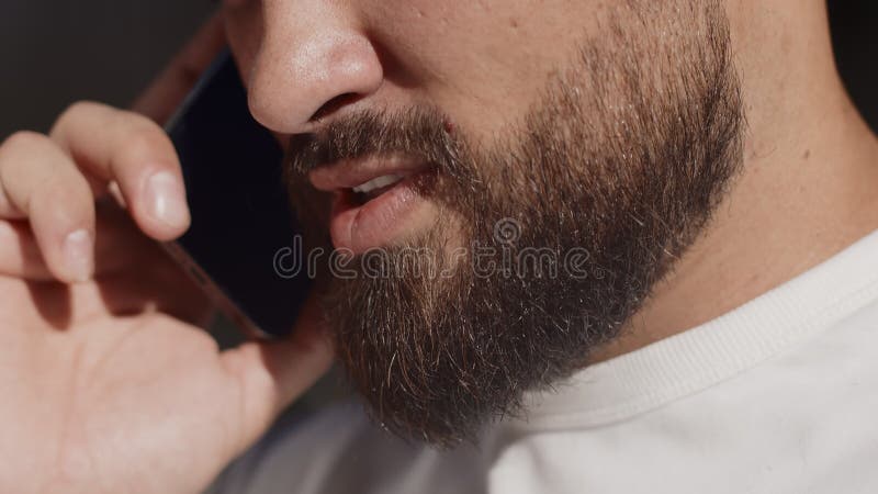 Young man close up talking with a friend on a smartphone and smiling contentedly outdoors on a sunny day. Concept of