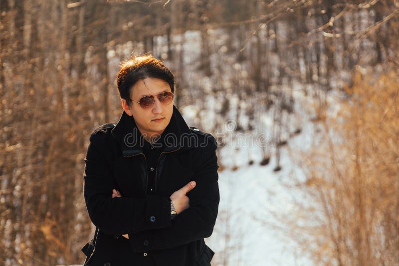 A young man in a coat and sunglasses in nature royalty free stock image A young man in a coat and sunglasses in nature royalty free stock image