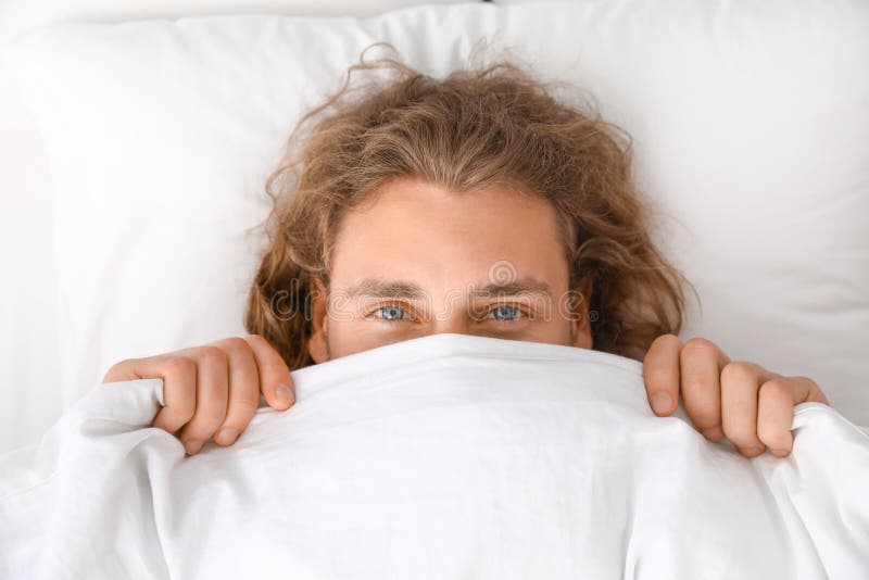 Young Man Covering His Face with Blanket while Lying on Pillow. Bedtime