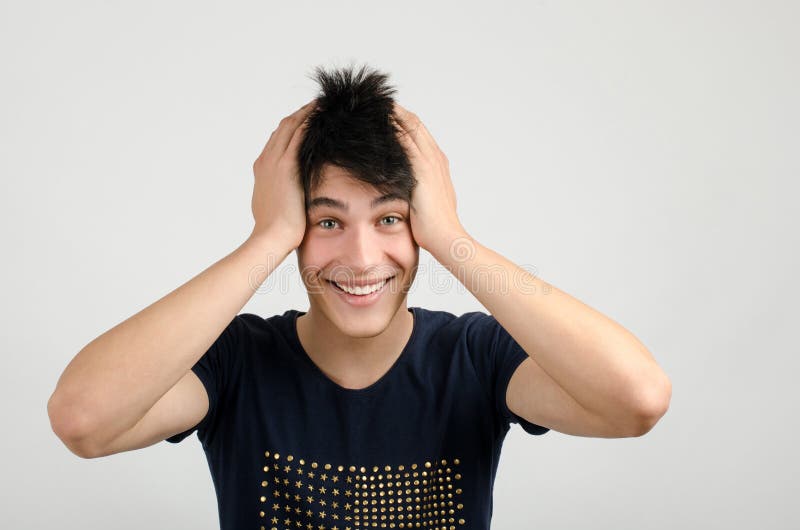 Молодой человек с сумасшедшими волосами держит голову улыбаясь. стоковое изображение