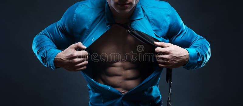 Young man displaying his abdominal muscles holding open his stylish blue shirt