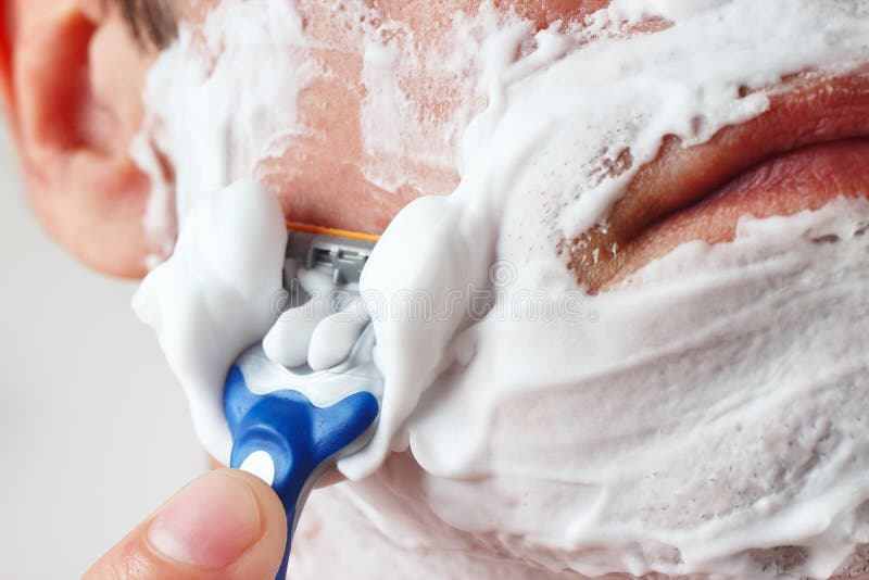 Young man with a disposable razor shaving his cheek closeup stock images Young man with a disposable razor shaving his cheek closeup stock images